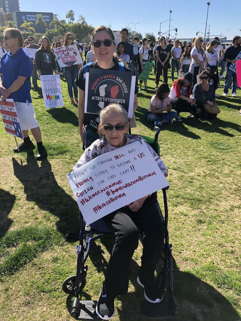 Immigrant American citizen mother in a wheelchair holding a sign at the 2019 Women’s March in San Diego.